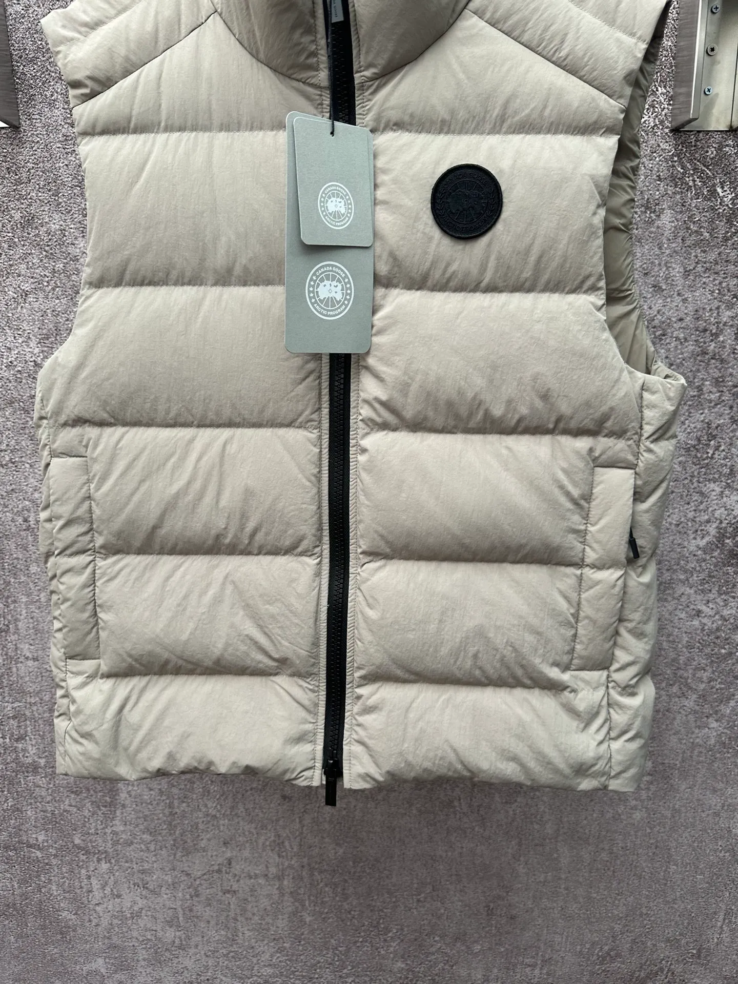 P720 Canada Goose Badge Down Vest Fabric selection: The use of high-quality protective nylon fabric not only enhances the wear resistance of the surface, but also takes into account wind resistance, ensuring excellent performance in various harsh weather conditions.  90 national standard high-quality white duck down: selected high-loft down, weighing 160g, light and warm, with excellent temperature locking performance and good resilience.  Three-dimensional quilting process: Precision thread reinforcement to prevent velvet drilling and ensure that the fluffy and resilient elasticity lasts as new.  Details: The ribbon is woven with polyester as the base, and the brand letters are decorated on the ribbon through high-precision computer embroidery. The edges of the pattern are clear, the stitches are fine and even, and multiple layers of embroidery thread are stacked to enhance the three-dimensional effect. Accessories: One-to-one customized logo, one-to-one customized zipper puller, one-to-one customized three-label SIZE: S M L XL